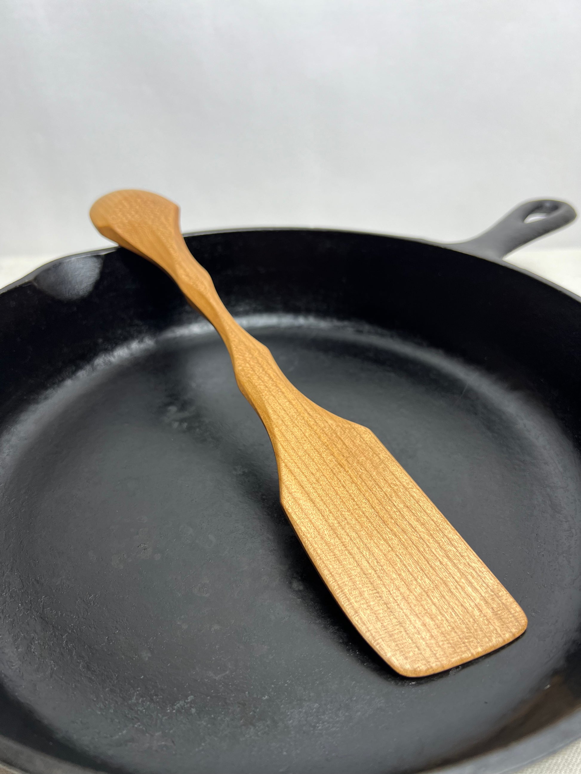 Wooden spatula on a black cast iron skillet with a light gray background